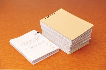 1 カ月間に受け取る請求書と振替伝票の束の比較。導入前(右)と比べ、導入後(左)は、1/5まで削減された